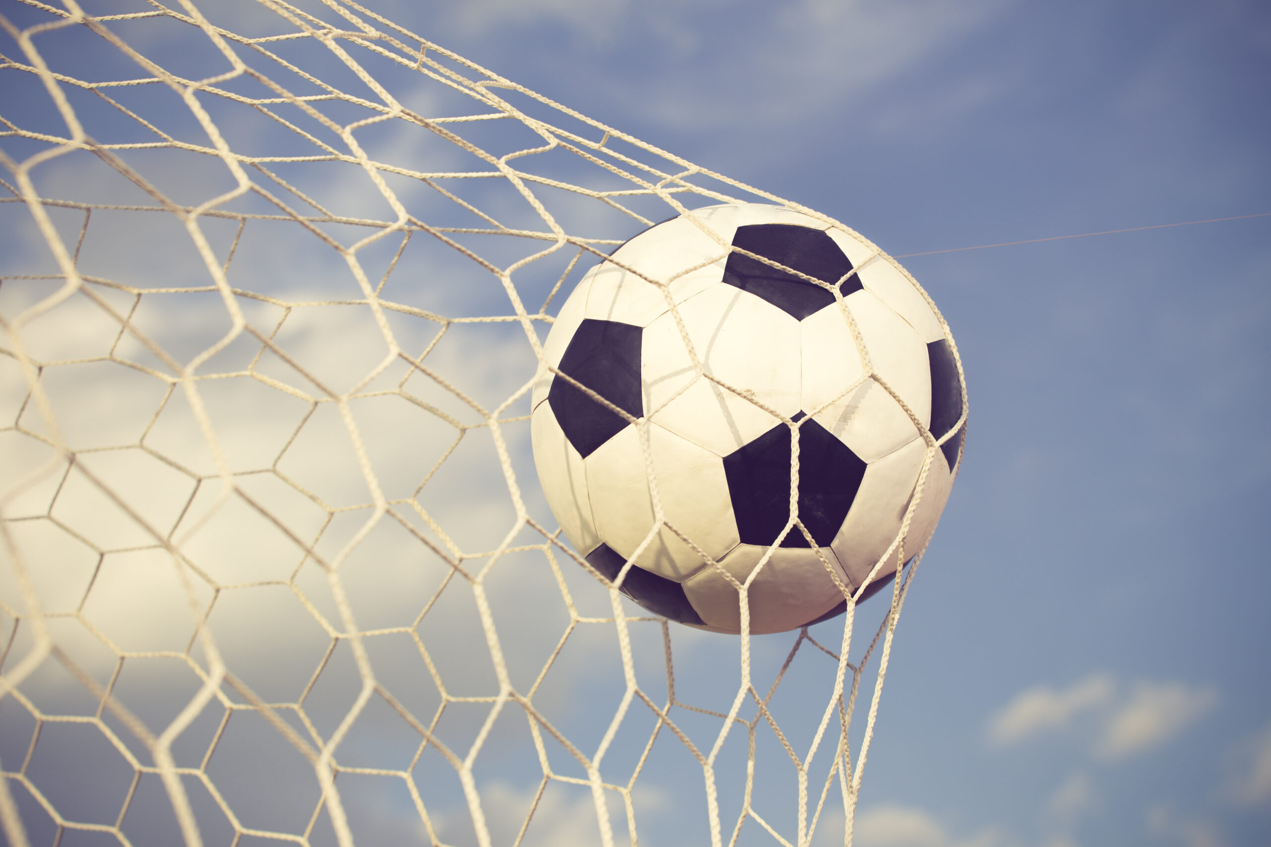 Soccer Ball Flies Into Net Against Cloudy Sky