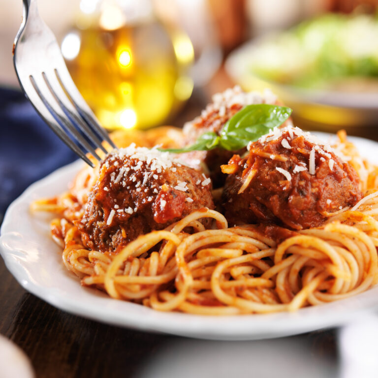 Spaghetti And Meatballs Topped With Cheese And Basil