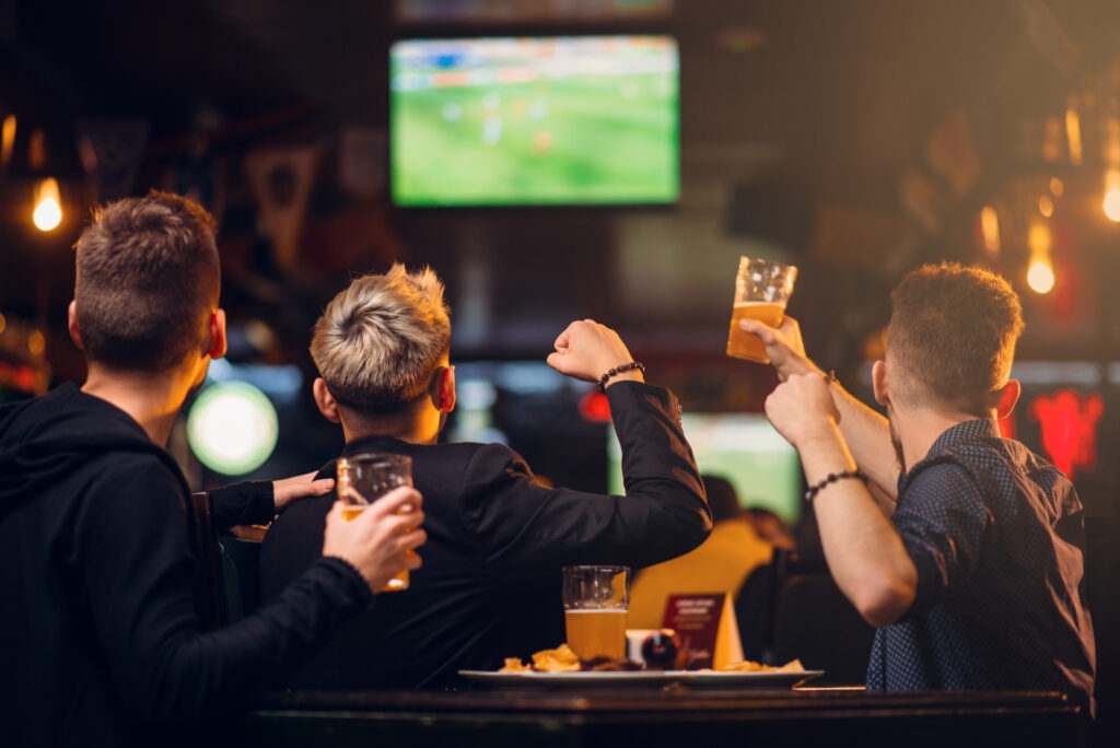 watch the World Cup in Brighton: Three men watches football on TV in a sport bar.