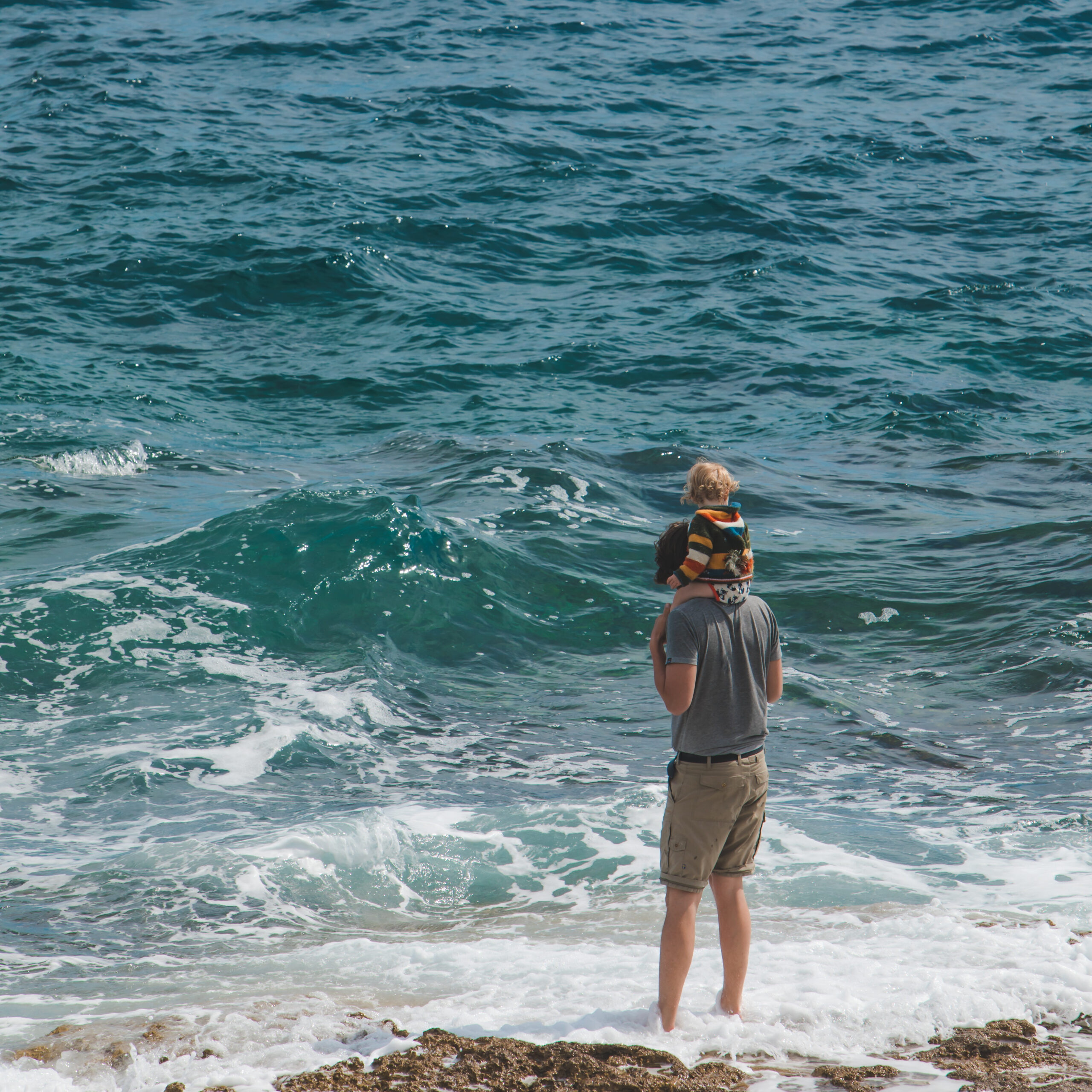 Young Father Holding Kid On Shoulders by the sea at Saltdean beach
