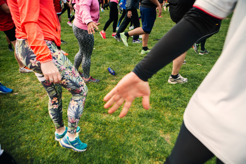 Active Adults Exercising Together On Grassy Field