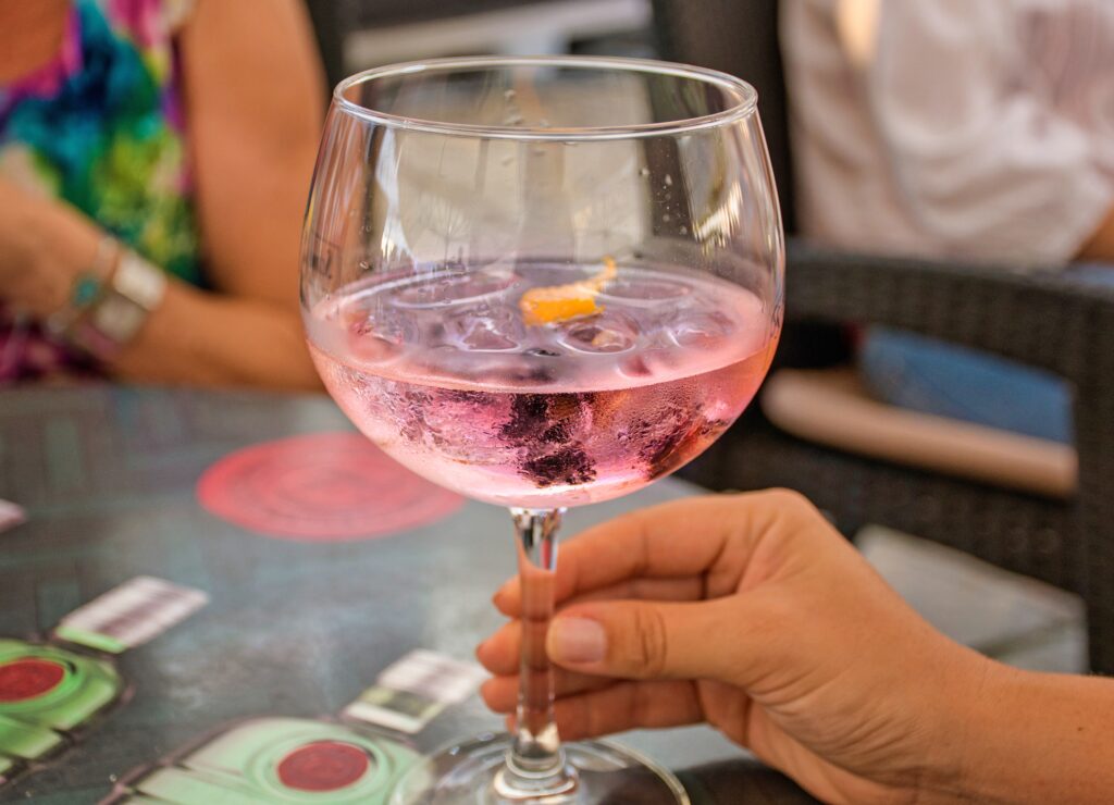 Close Up Image Of Hand Holding Glass Of Pink Gin at one of the gin bars in Brighton