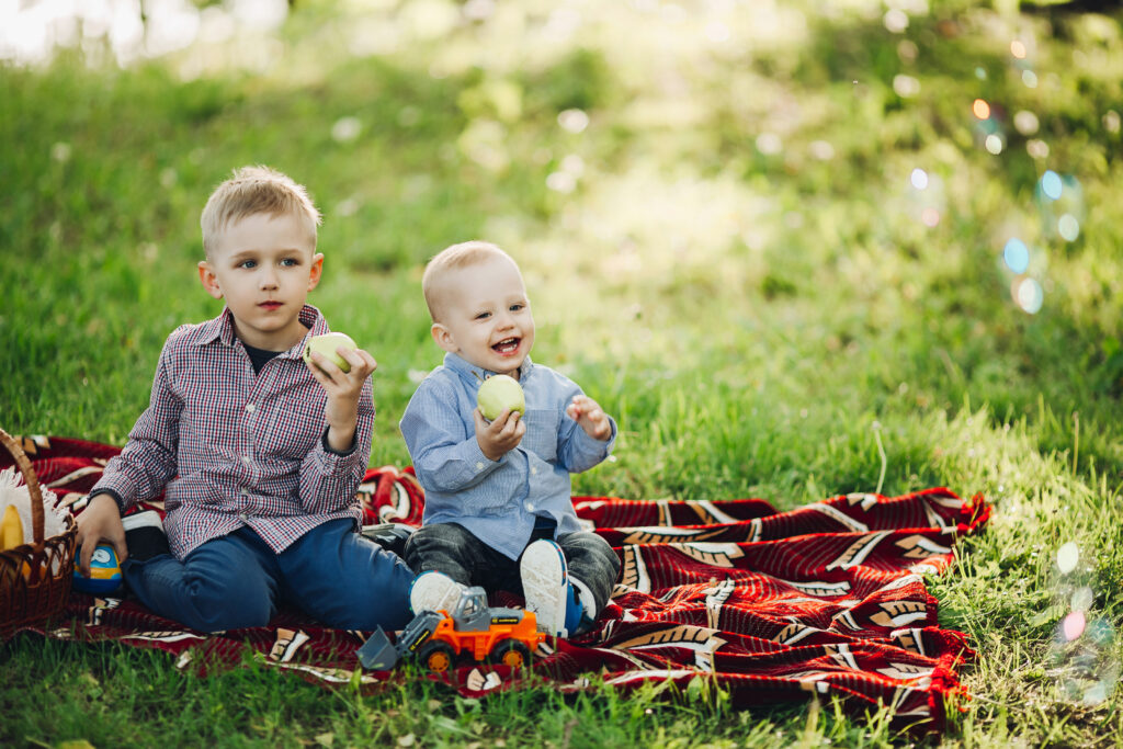 2 children eating an apple at a picnic in the park
