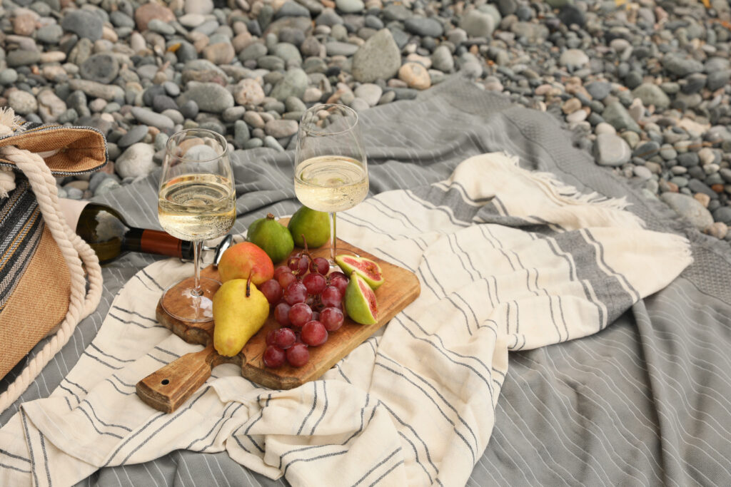 White wine and fresh fruits on picnic blanket outdoors