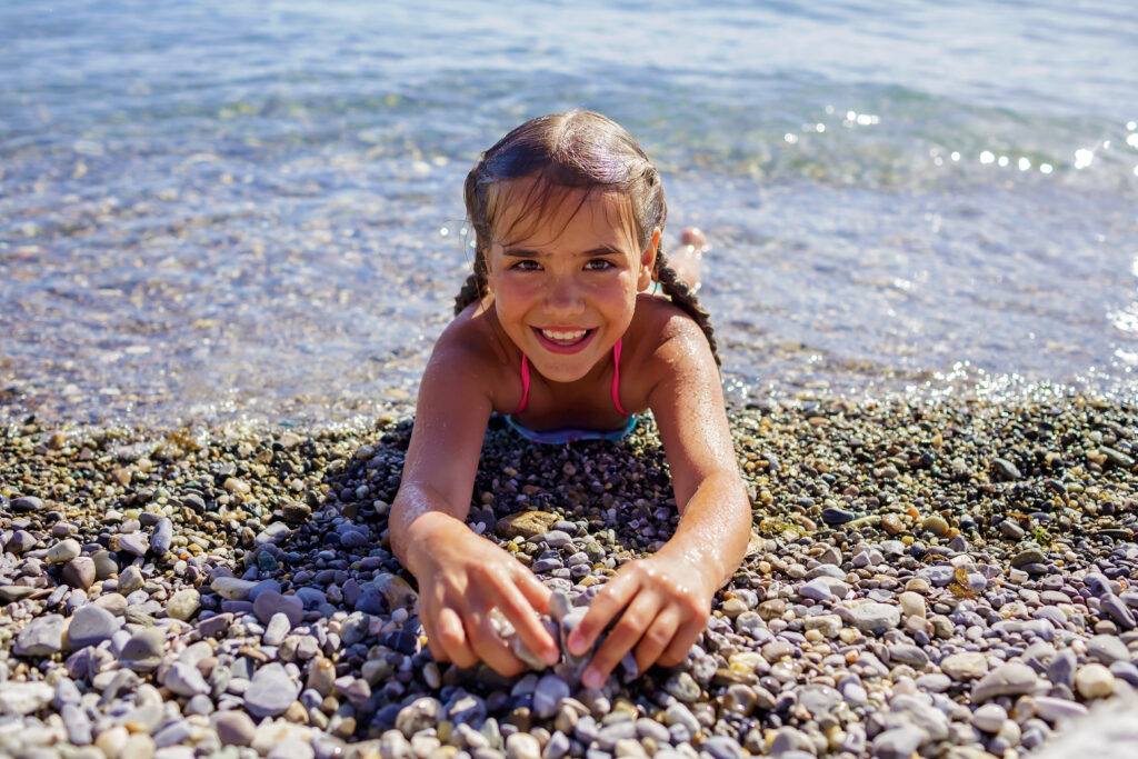 Portrait of happy girl has fun on pebble beach