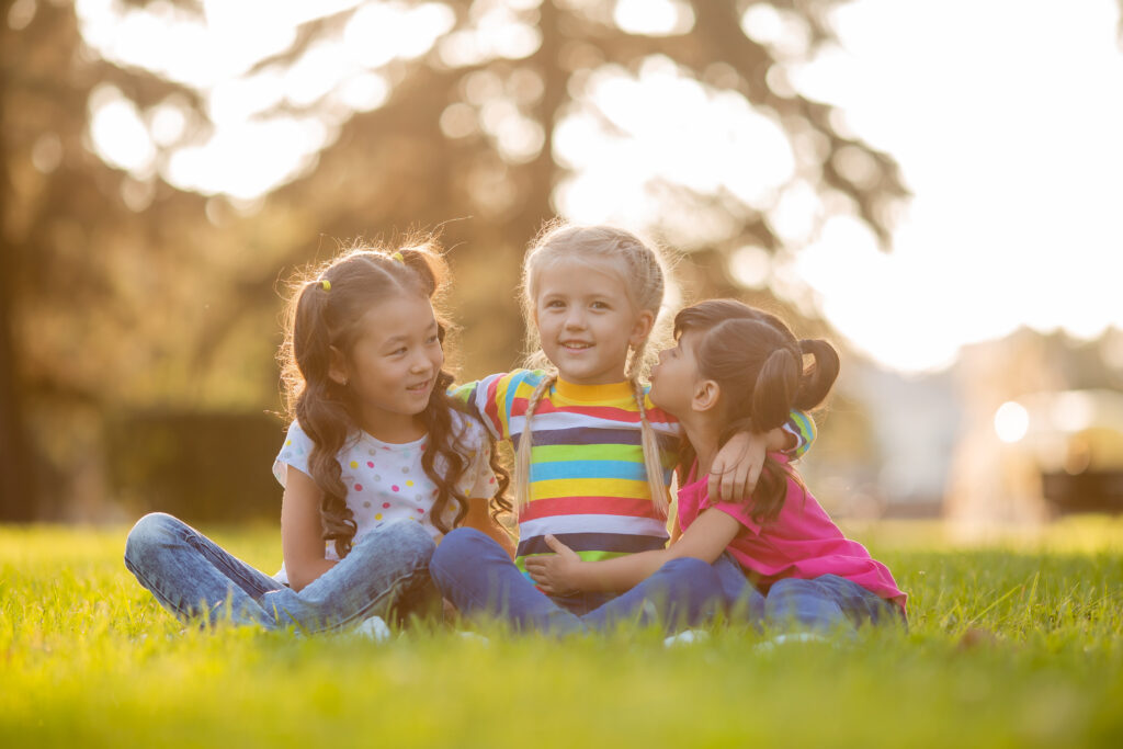 Girls Playfully Embrace Each Other On Green Grass