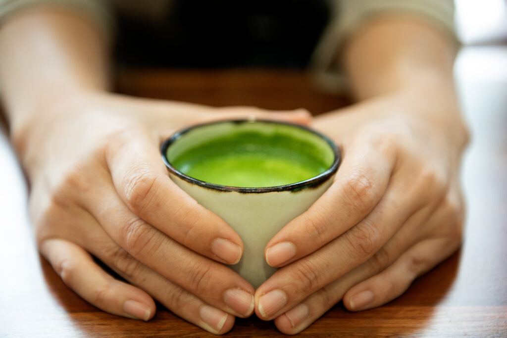 Hand Holding A Glass Of Green Tea