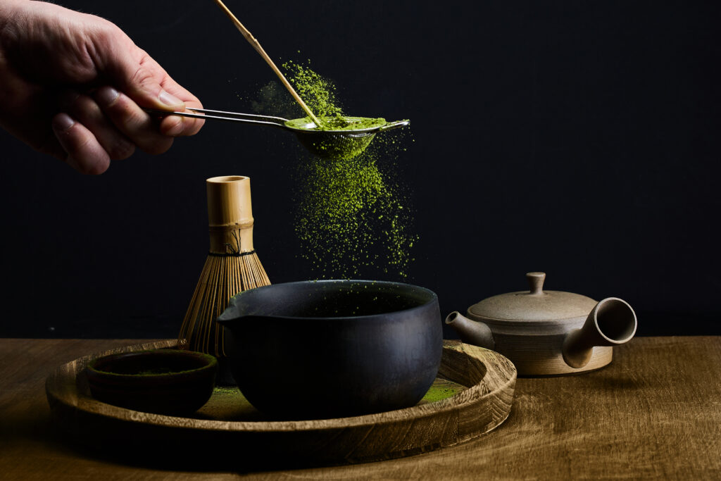A serene matcha tea setup with traditional tools on a dark background.