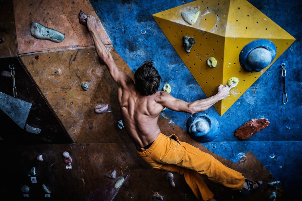 Muscular man practicing rock-climbing on a rock wall indoors