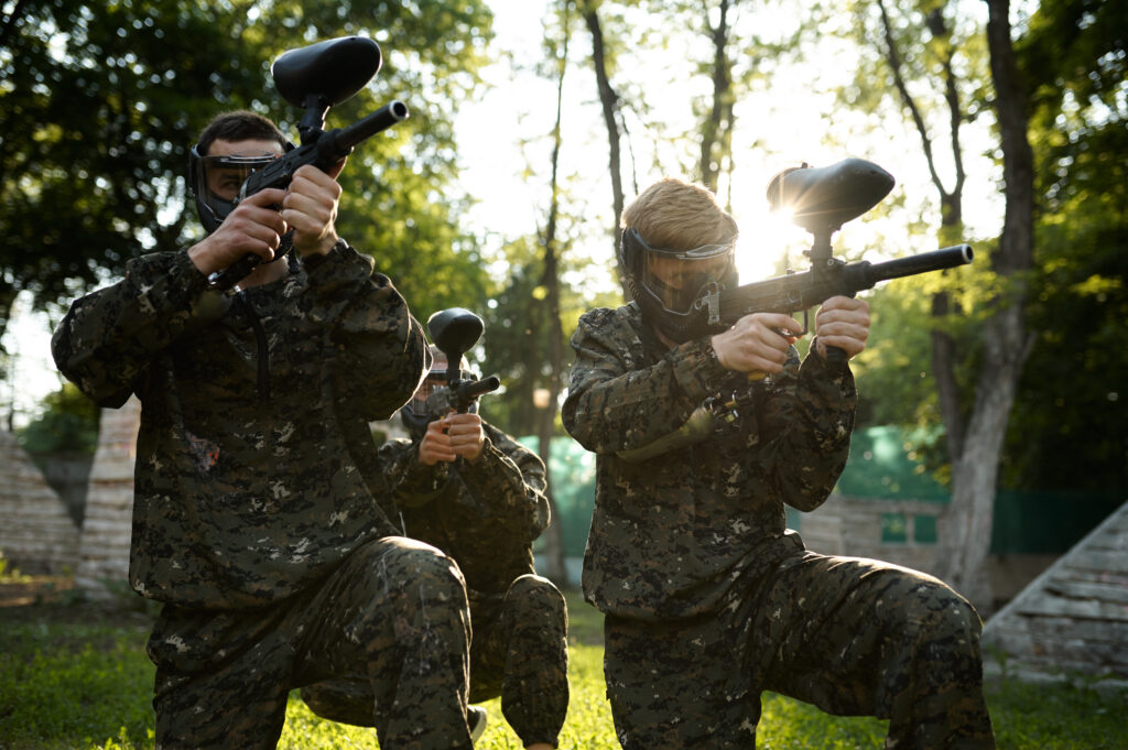 Paintball team in masks, battle on playground in the forest.