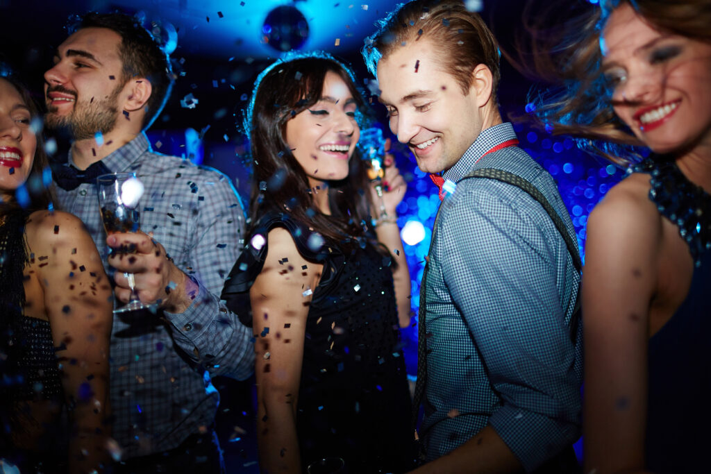 Happy couple and their friends dancing under confetti rain at disco