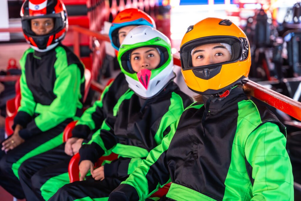 Teenagers Wearing Racing Suits And Helmets Awaiting Go Karting Near Brighton