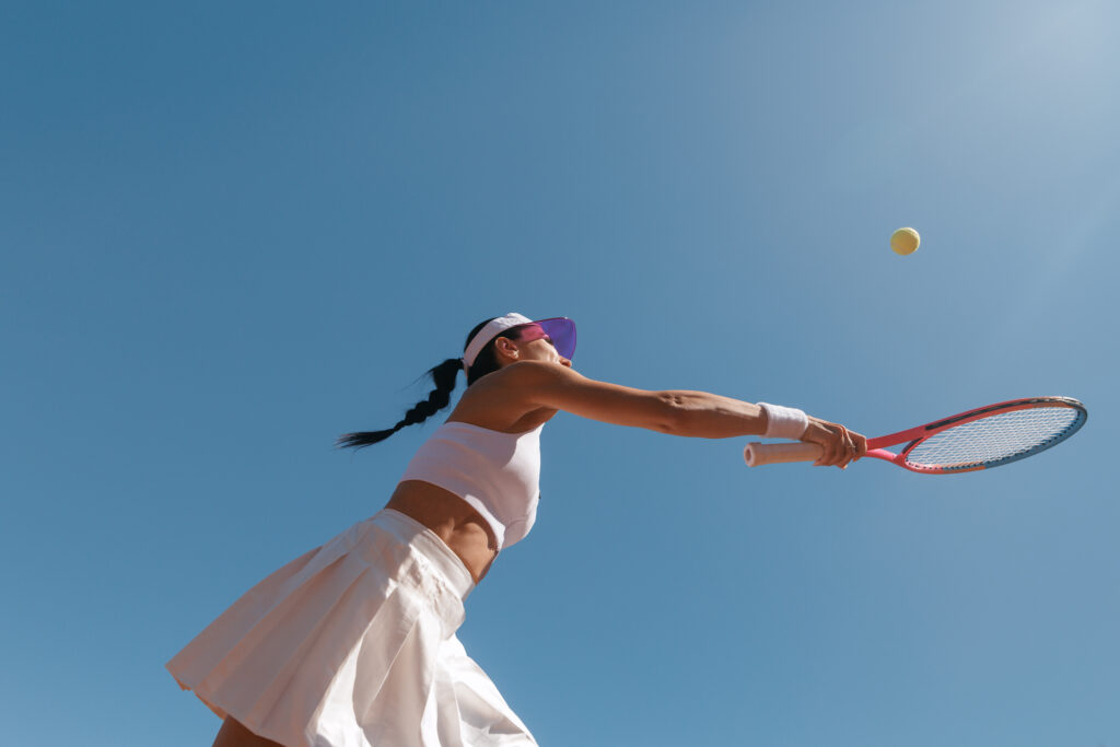 Woman Playing Tennis Against Blue Sky Backdrop